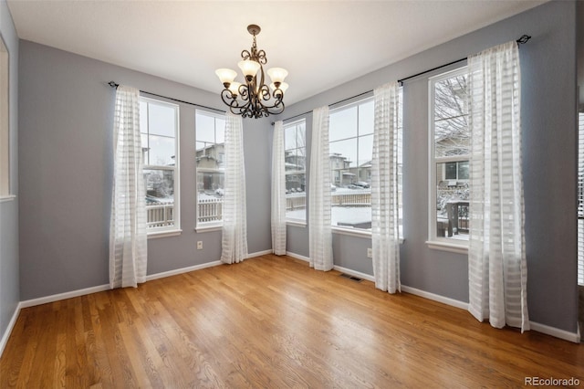 unfurnished dining area with hardwood / wood-style floors and a notable chandelier