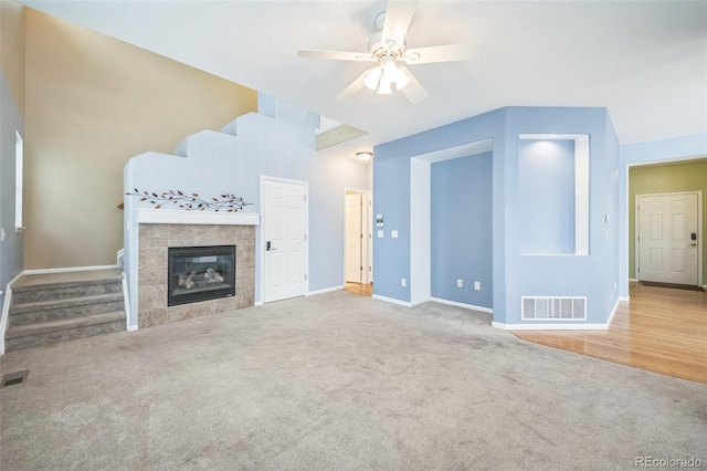 unfurnished living room with carpet flooring, ceiling fan, and a tiled fireplace