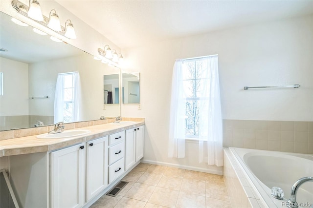 bathroom with tile patterned floors, vanity, and tiled tub