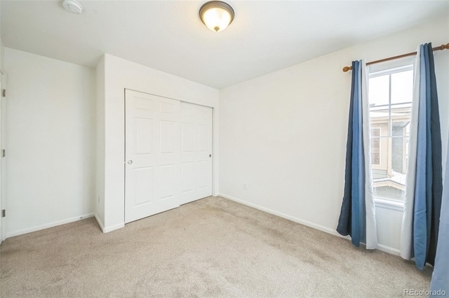 unfurnished bedroom with a closet and light colored carpet