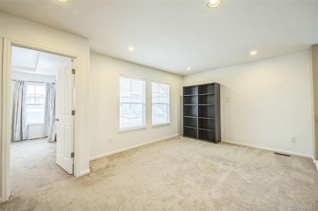 spare room featuring light colored carpet and plenty of natural light