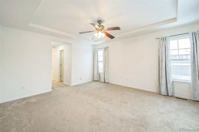 carpeted spare room featuring a tray ceiling and ceiling fan