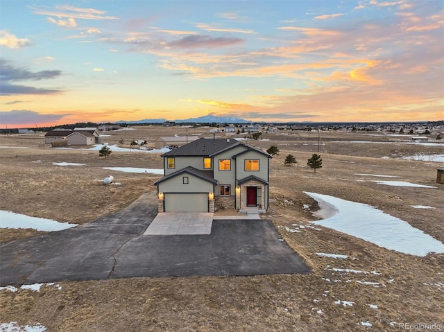 view of front of home featuring an attached garage, concrete driveway, and stone siding