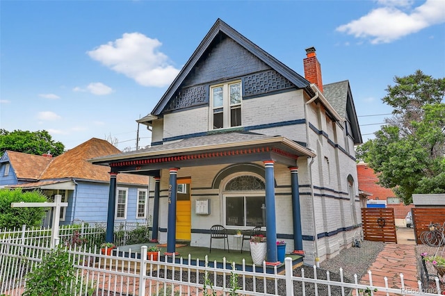 274 S Lincoln St, Denver, CO 80209 - victorian home with covered porch, a chimney, a fenced front yard, and a shingled roof