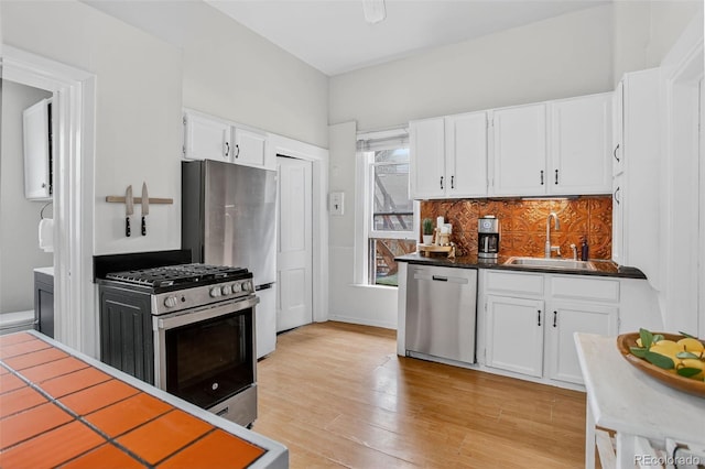 274 S Lincoln St, Denver, CO 80209 - kitchen featuring appliances with stainless steel finishes, white cabinetry, backsplash, light wood-style floors, and dark countertops