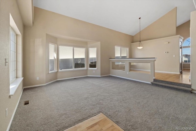 unfurnished living room with visible vents, baseboards, high vaulted ceiling, and carpet flooring