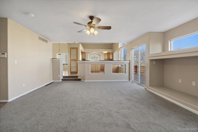 unfurnished living room with carpet flooring, baseboards, visible vents, and ceiling fan