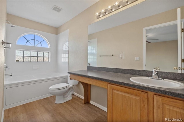 full bathroom featuring visible vents, toilet, wood finished floors, a bath, and vanity