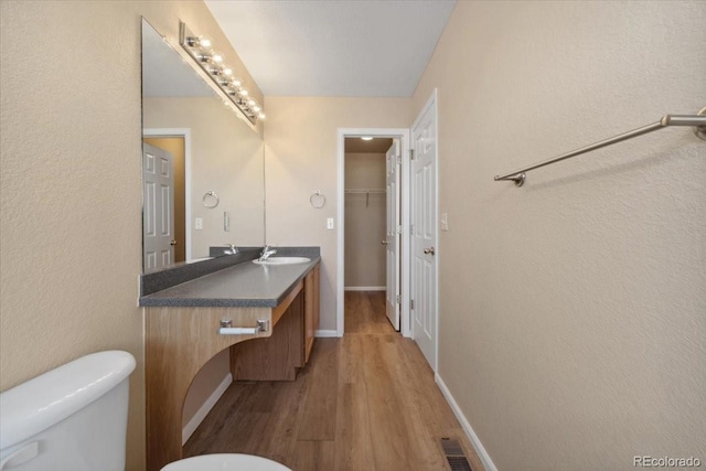 bathroom featuring visible vents, toilet, wood finished floors, baseboards, and vanity