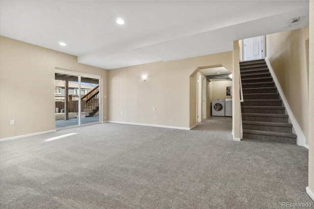 basement featuring washing machine and clothes dryer, stairway, arched walkways, and baseboards