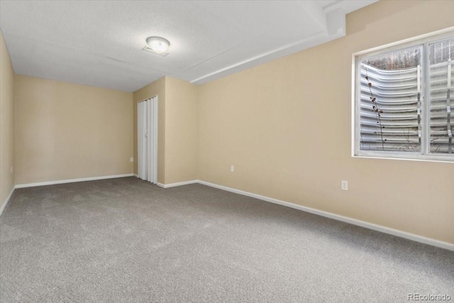 carpeted spare room with baseboards and a textured ceiling