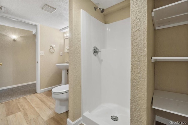 full bath featuring visible vents, a shower stall, baseboards, toilet, and wood finished floors