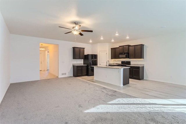 kitchen with sink, ceiling fan, a kitchen island with sink, dark brown cabinets, and black appliances