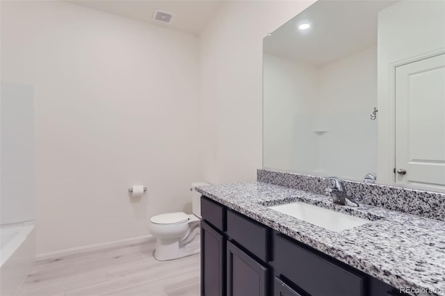 bathroom with hardwood / wood-style flooring, vanity, toilet, and a bathing tub