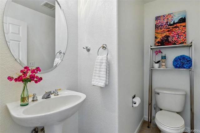 bathroom featuring visible vents, a sink, tile patterned floors, baseboards, and toilet