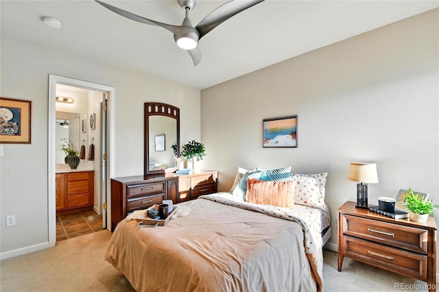 bedroom with baseboards, ensuite bathroom, a ceiling fan, and light colored carpet