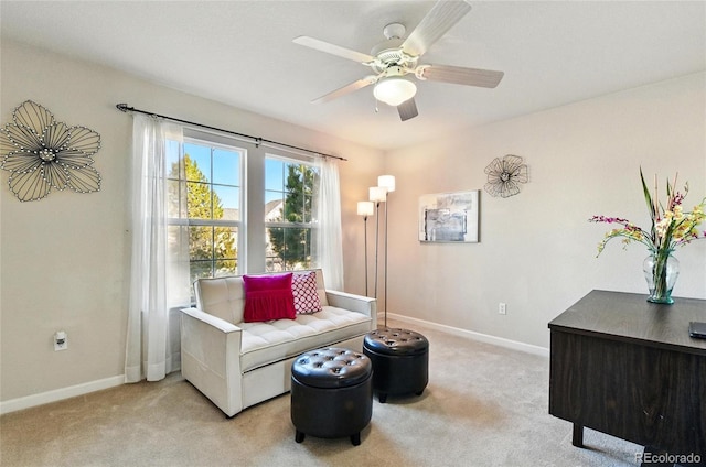 living area featuring a ceiling fan, baseboards, and light colored carpet