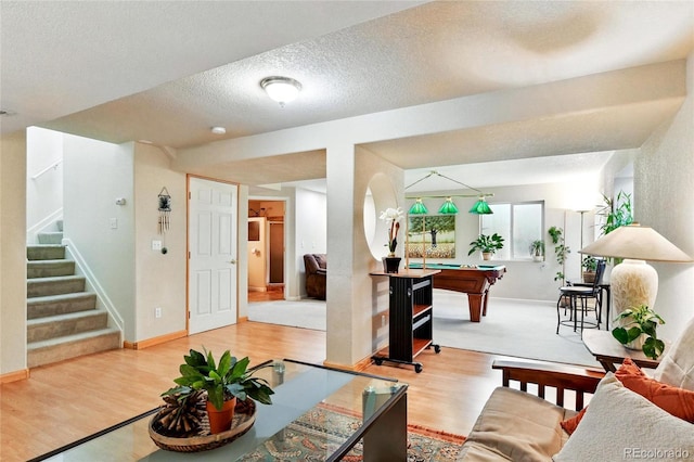 living room with a textured ceiling, baseboards, billiards, wood finished floors, and stairway