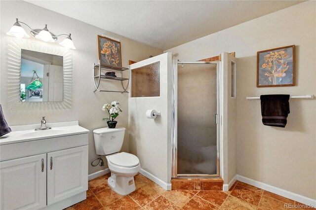 bathroom featuring vanity, baseboards, a stall shower, and toilet