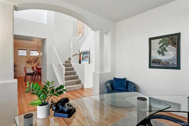 dining area featuring stairway, arched walkways, wood finished floors, and a chandelier