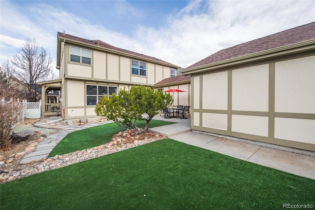 back of property with a lawn, a patio area, and stucco siding