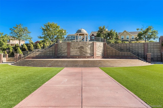 view of community featuring a lawn and fence