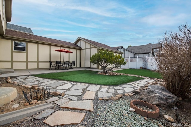view of yard featuring a patio area, fence, and an outbuilding