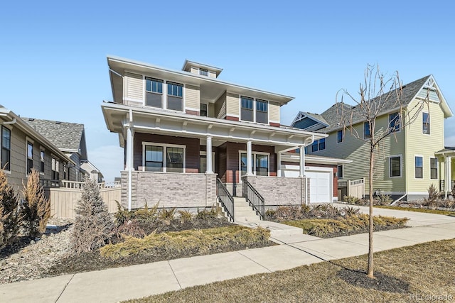 american foursquare style home featuring brick siding, a porch, driveway, and fence