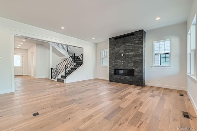 unfurnished living room with recessed lighting, stairway, light wood-style flooring, and baseboards