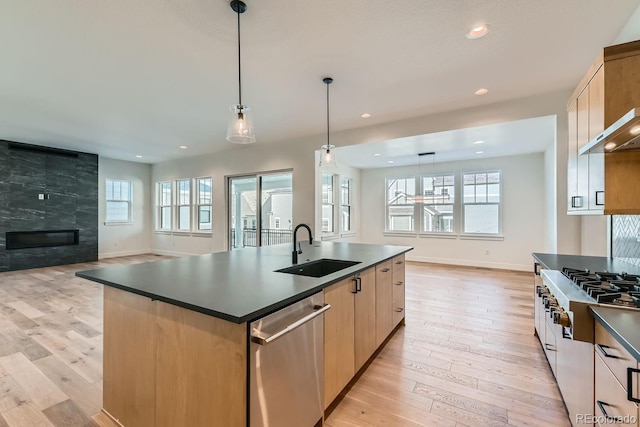 kitchen featuring a sink, dark countertops, open floor plan, a fireplace, and dishwasher