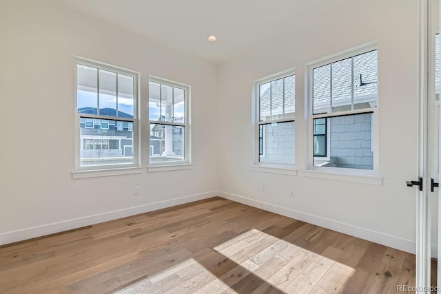 empty room featuring recessed lighting, baseboards, and light wood-type flooring