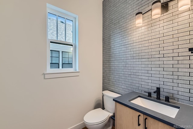 half bath with vanity, baseboards, decorative backsplash, tile walls, and toilet