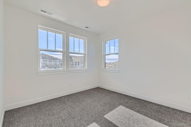 empty room with baseboards, visible vents, and carpet floors