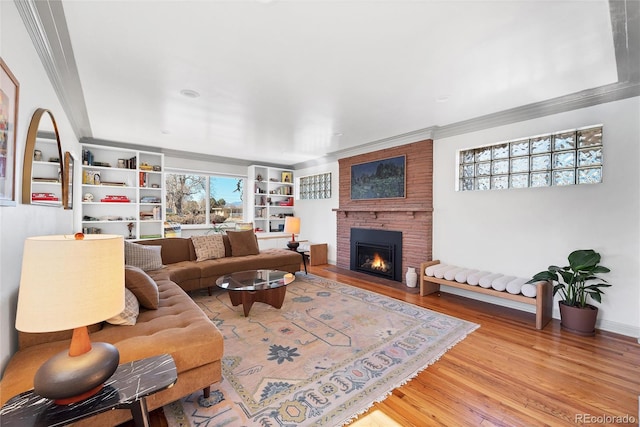 living room featuring ornamental molding, a brick fireplace, and wood finished floors