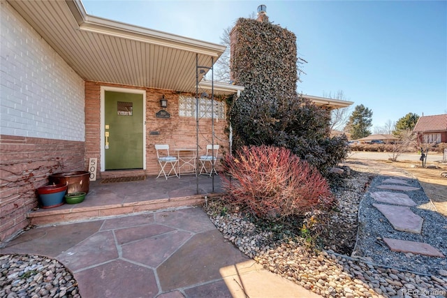 view of exterior entry with a patio area and brick siding