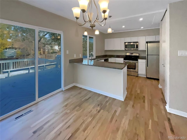 kitchen featuring kitchen peninsula, appliances with stainless steel finishes, white cabinetry, light hardwood / wood-style flooring, and pendant lighting