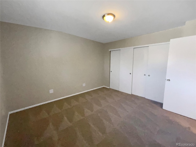 unfurnished bedroom featuring dark carpet and a closet