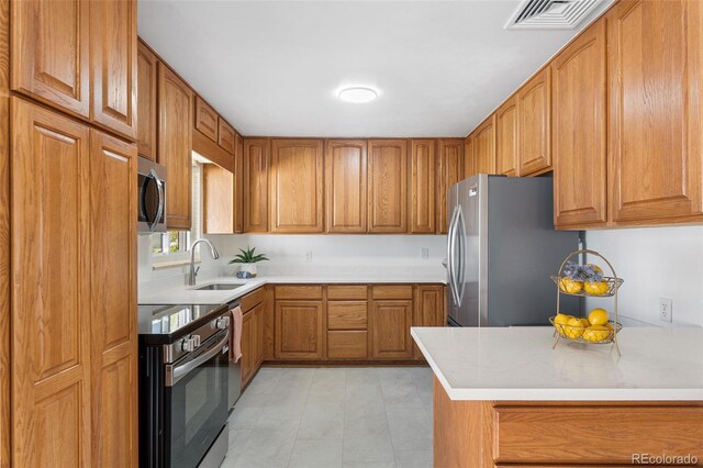6506 Lee St, Arvada, CO 80004 - kitchen featuring appliances with stainless steel finishes, a sink, brown cabinetry, and light countertops