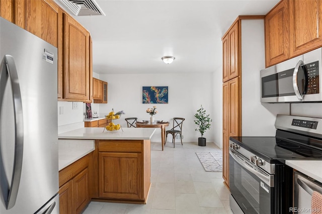 6506 Lee St, Arvada, CO 80004 - kitchen with appliances with stainless steel finishes, a peninsula, light countertops, and brown cabinets