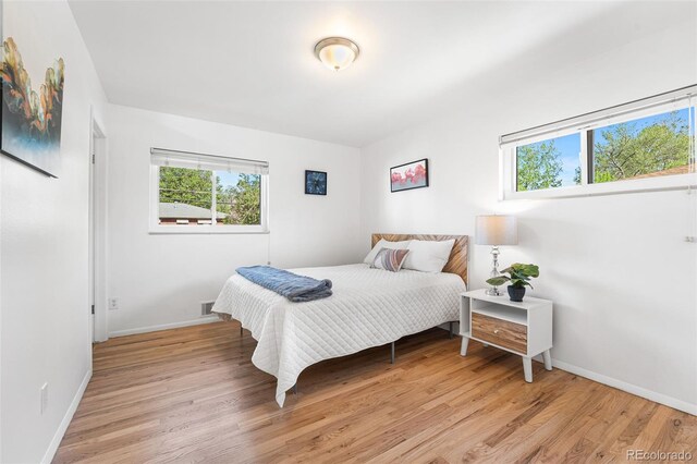 6506 Lee St, Arvada, CO 80004 - bedroom with multiple windows, light wood-style flooring, and baseboards
