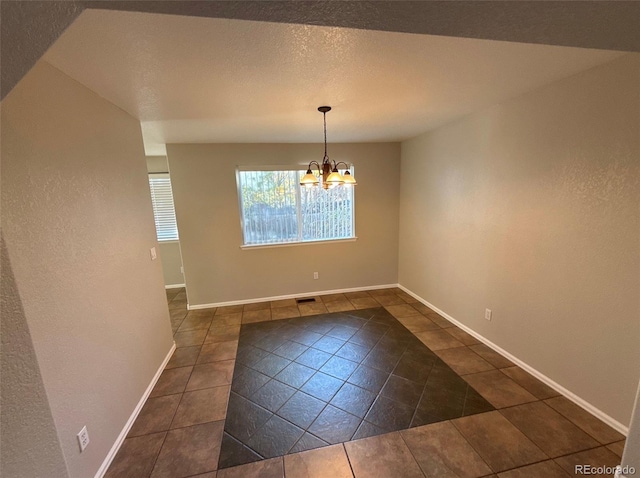 unfurnished dining area with dark tile patterned flooring and a notable chandelier