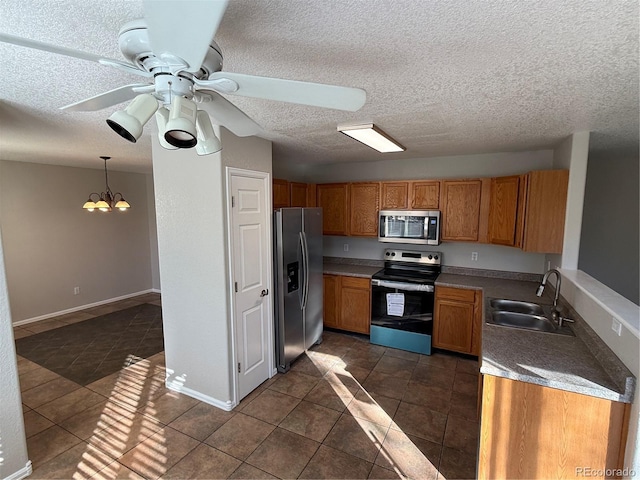 kitchen featuring appliances with stainless steel finishes, a textured ceiling, pendant lighting, and sink