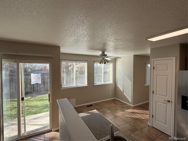 interior space with a textured ceiling, tile patterned floors, plenty of natural light, and ceiling fan