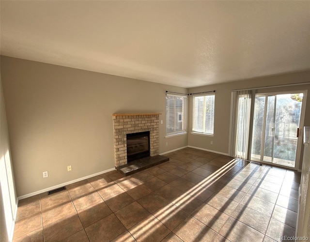 unfurnished living room featuring a fireplace and dark tile patterned flooring