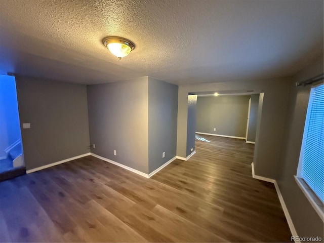 empty room with dark hardwood / wood-style flooring and a textured ceiling