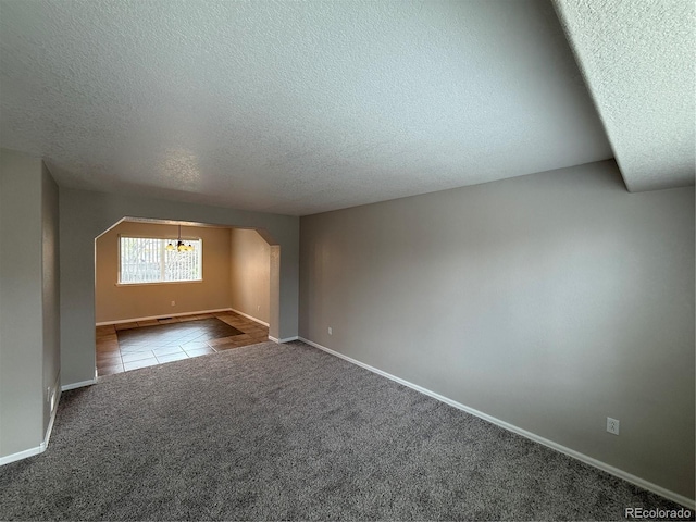 13031 Dexter St, Thornton, CO 80241 - carpeted spare room featuring a textured ceiling, arched walkways, tile patterned floors, baseboards, and a chandelier