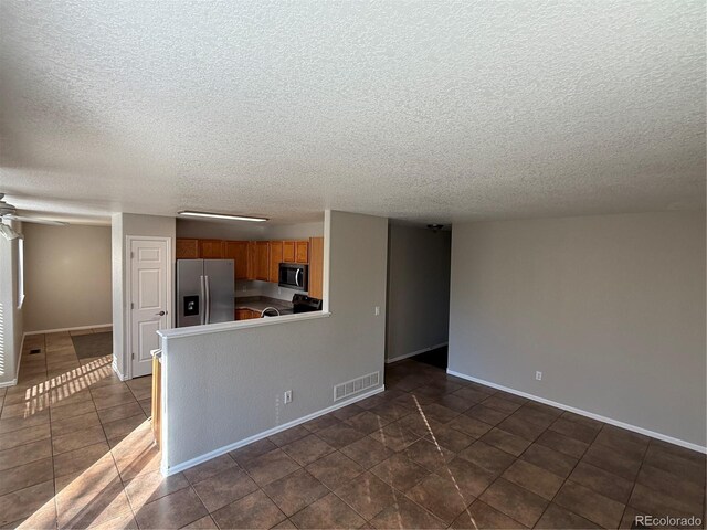13031 Dexter St, Thornton, CO 80241 - unfurnished living room with a textured ceiling, baseboards, and dark tile patterned flooring