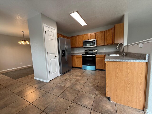 13031 Dexter St, Thornton, CO 80241 - kitchen with stainless steel appliances, a sink, a chandelier, dark tile patterned floors, and a textured ceiling