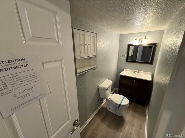 13031 Dexter St, Thornton, CO 80241 - bathroom with a textured wall, a textured ceiling, wood finished floors, toilet, and vanity