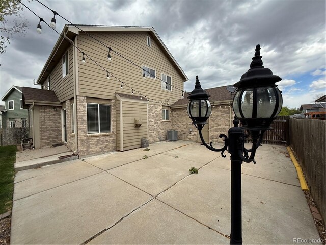 13031 Dexter St, Thornton, CO 80241 - rear view of house with brick siding, a patio, a fenced backyard, and central AC